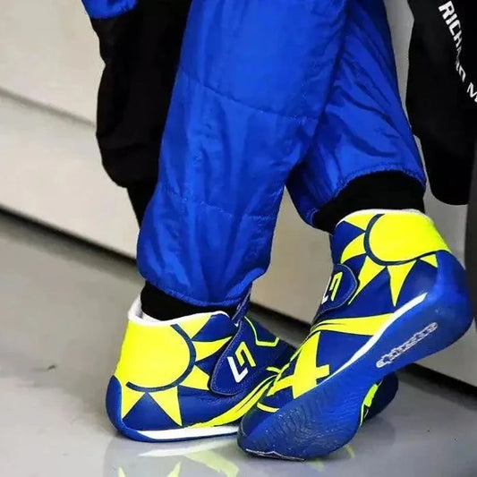 Blue and yellow Lando Norris 2023 F1 Race shoes with sun design worn by a person in blue pants.