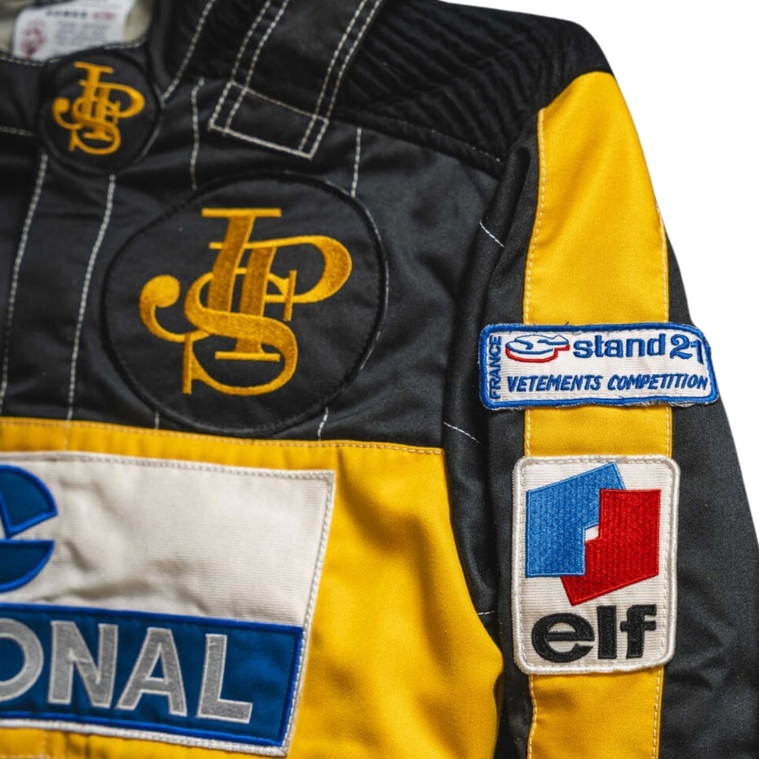 Close-up detail of the Ayrton Senna 1985 F1 racing suit fabric and stitching, showcasing vintage craftsmanship and sponsor detailing.