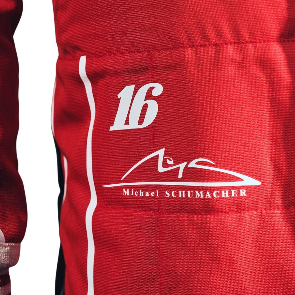 Close-up of a red racing suit with a white vertical stripe, the number 16, and a white Michael Schumacher signature graphic.
