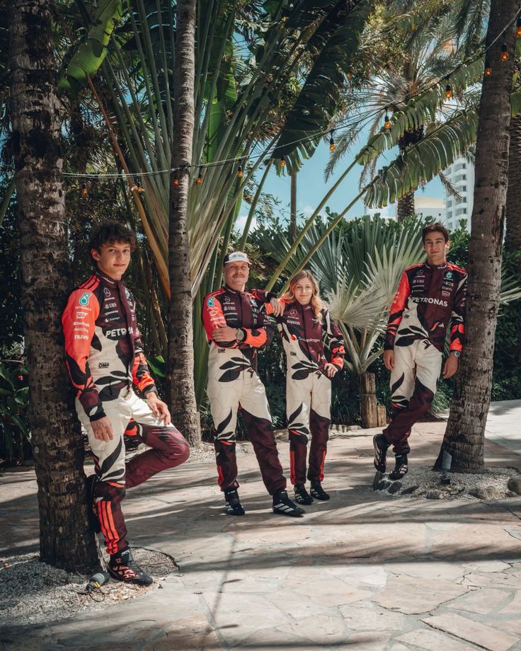 Four people, George, Valtteri, Doriane, and Kimi, in matching 2025 Mercedes Miami GP F1 outfits, standing among palm trees.