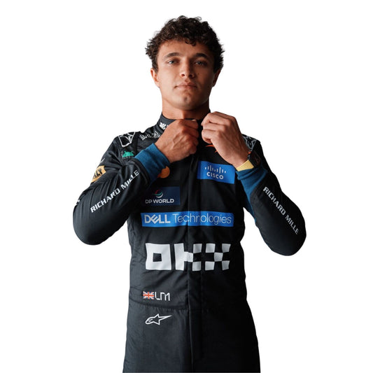 A Lando Norris wearing a black racing suit with multiple sponsor logos, including Dell Technologies, OKX, and Alpinestars, adjusting the collar of the suit against a plain white background.