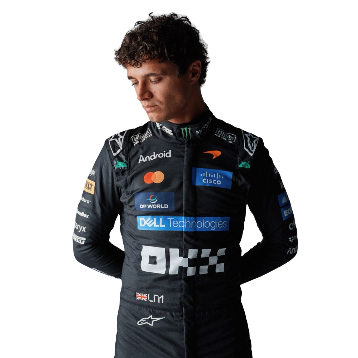A Lando Norris wearing a black racing suit with multiple sponsor logos, including Monster Energy, Mastercard, Oracle, and Dell Technologies, photographed against a solid white background.