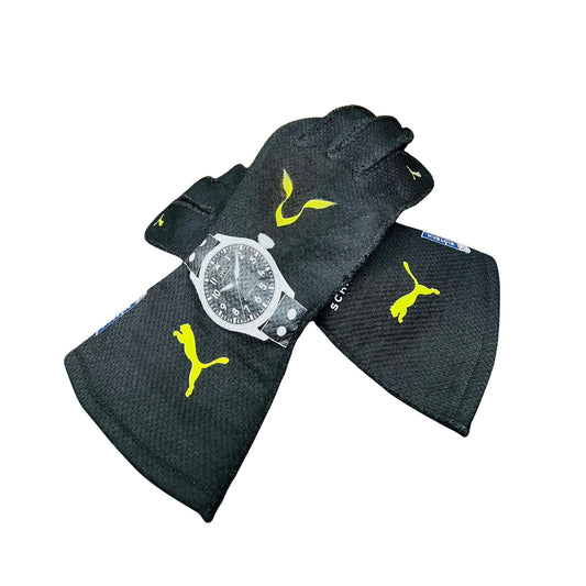 Black Lewis Hamilton 2022 F1 race gloves with yellow Puma logo and a watch on a white background