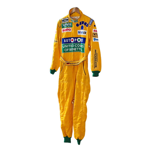 Front view of Michael Schumacher's 1992 F1 racing suit featuring deep green with yellow accents, signature Benetton sponsorship, and classic zip-front design.