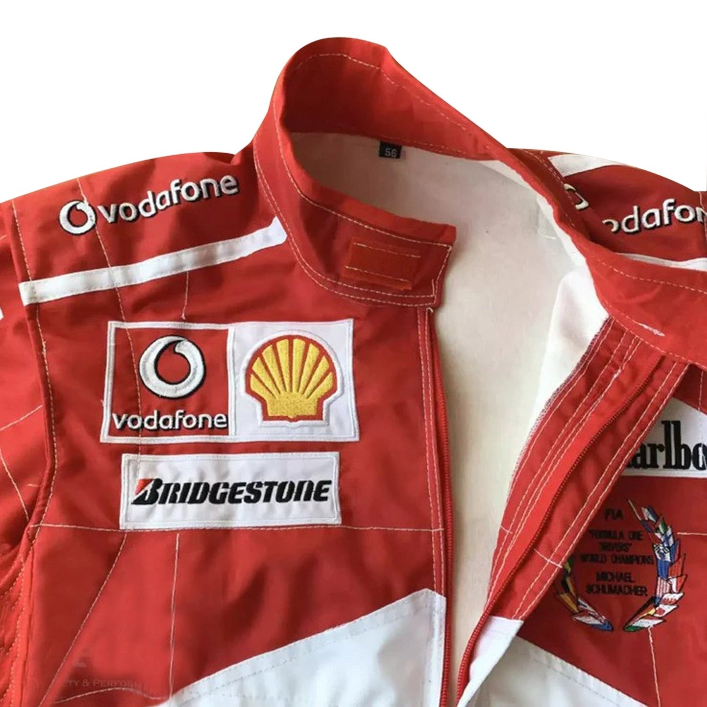 Close-up of the 2005 Schumacher suit highlighting fine embroidery, Ferrari red color tone, and precise stitching on race-worn sponsor badges.