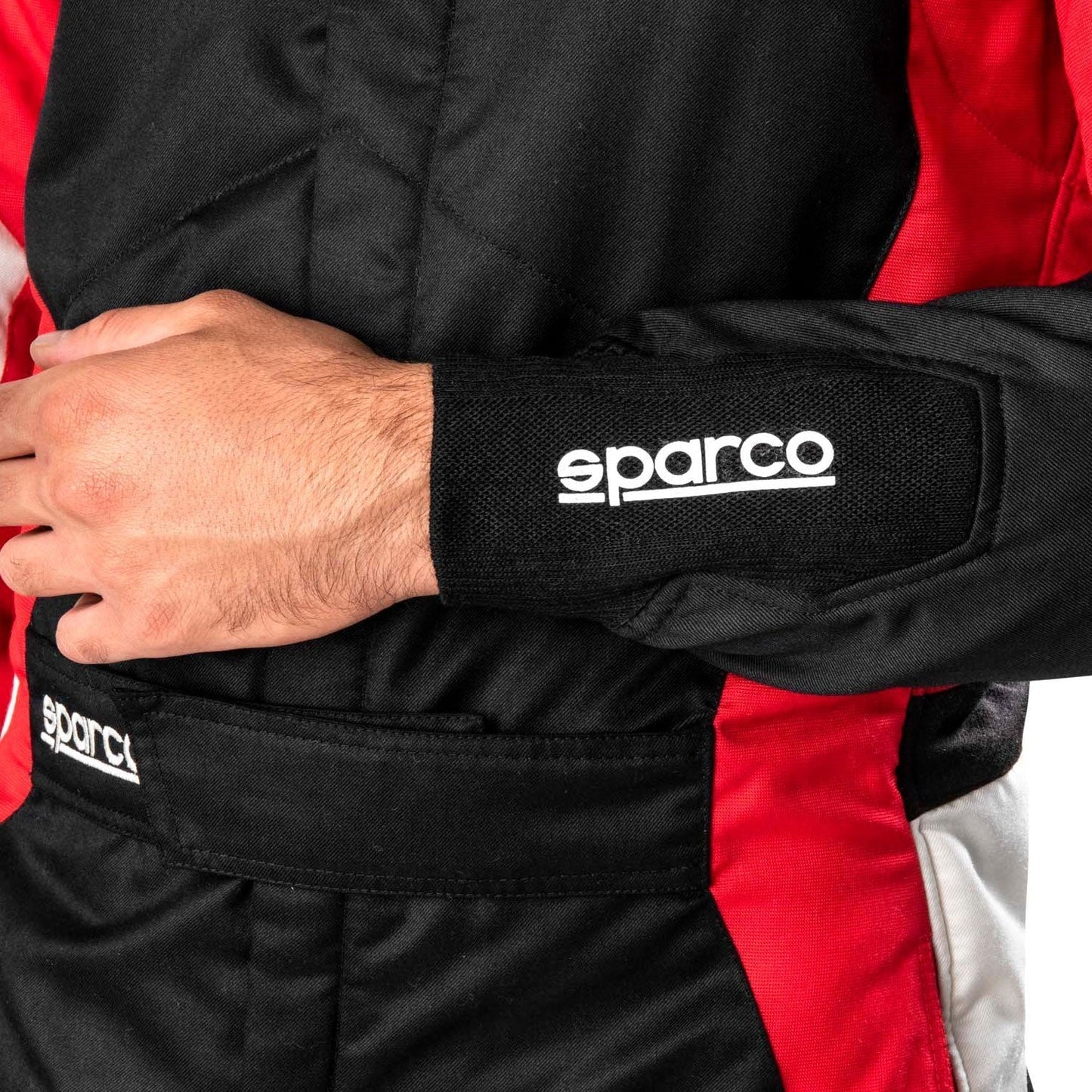 Close-up of a person wearing a black and red Sparco racing suit with visible branding.