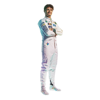 Lando Norris wearing a white and light blue racing suit with multiple sponsor logos stands with arms crossed against a plain white background.
