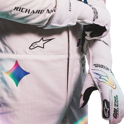 oscar piastri wearing a white racing suit with multiple sponsor logos against a plain white background.